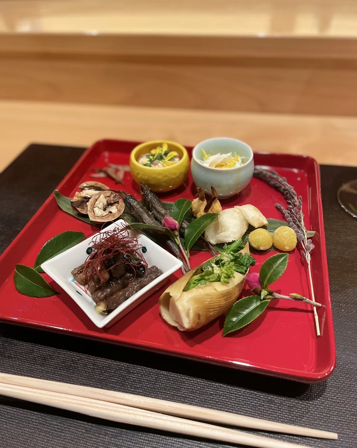 朱の盆に盛った八寸。小鉢と季節の葉