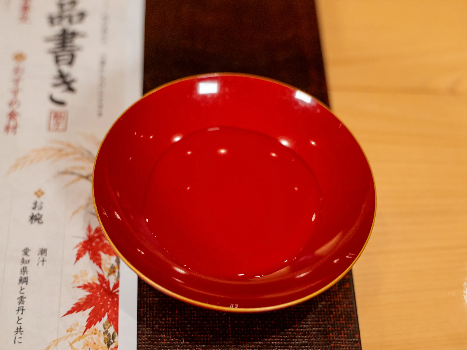 品書きの横に置いた朱塗りの盃の食前酒
